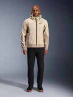 Alpinestars Radium Tech Hoodie in Mastic Aluminum, urbaner Motorrad-Hoodie, getragen von einem männlichen Model mit schwarzer Hose und schwarzen Stiefeln, mit durchgehendem schwarzem Reißverschluss, kleinem Brustlogo und athletischer Passform für Stadtfahrten.