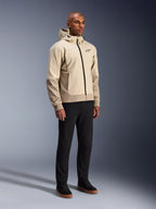 Alpinestars Radium Tech Hoodie, urbane Motorradjacke, Mastic Aluminum Hellbeige, getragen mit schwarzer Hose und schwarzen High-Top-Sneakern, mit technischer winddichter Außenschicht, Frontreißverschluss und abnehmbarer Kapuze, modernes Streetwear-Design für urbanes Fahren