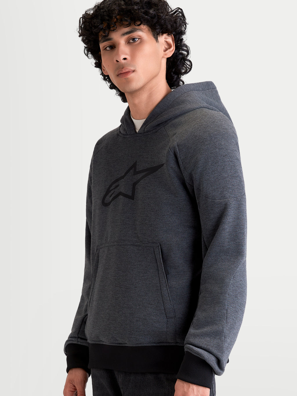 Alpinestars Ageless Hoodie, men's urban motorcycle hoodie jacket in asphalt melange gray, featuring front pouch pocket and fixed hood, worn by a model in an on-bike posture