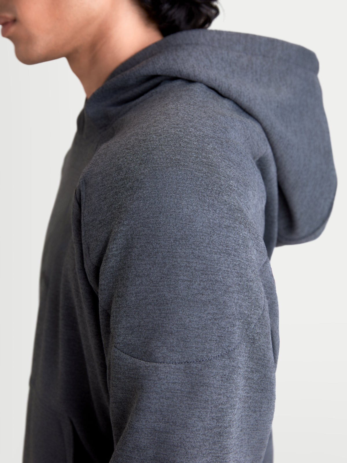 Alpinestars Ageless Hoodie, men's urban motorcycle riding hoodie in asphalt melange gray, close-up side profile view showing the knitted fabric construction and shoulder reinforcement details on a model