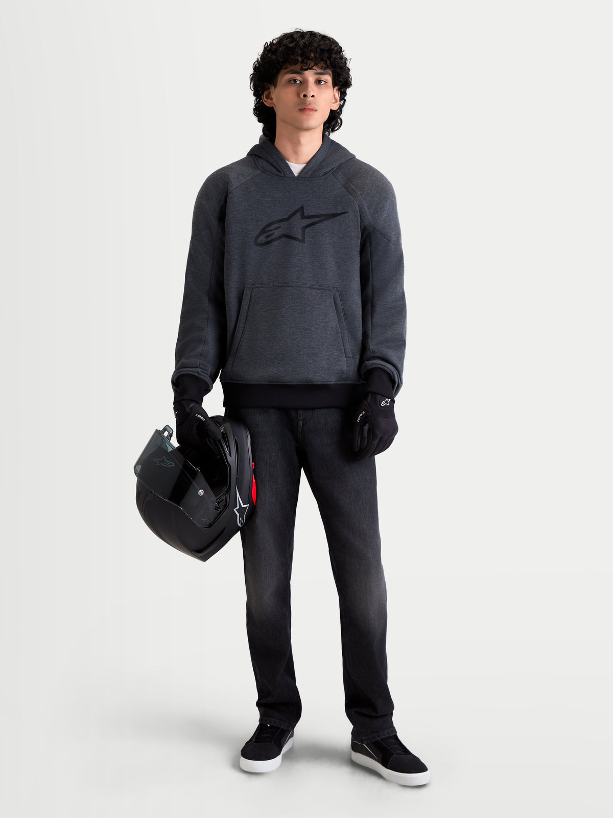 Alpinestars Ageless Hoodie, men's urban motorcycle hoodie in asphalt melange gray, front view on a model wearing black riding gloves and holding a helmet, featuring integrated shoulder and elbow protection.