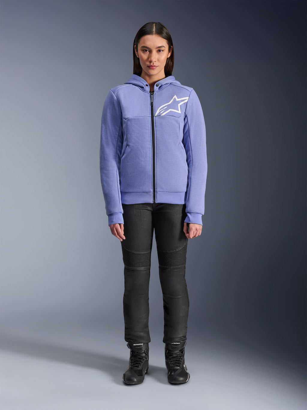 Alpinestars Stella Chrome V2 Sport Hoodie voor dames, Blue Violet met wit Astars-logo op de borst, technische fleece met volledige ritssluiting en capuchon, gedragen met zwarte motorbroek en motorlaarzen, casual stedelijke motorkleding voor dames