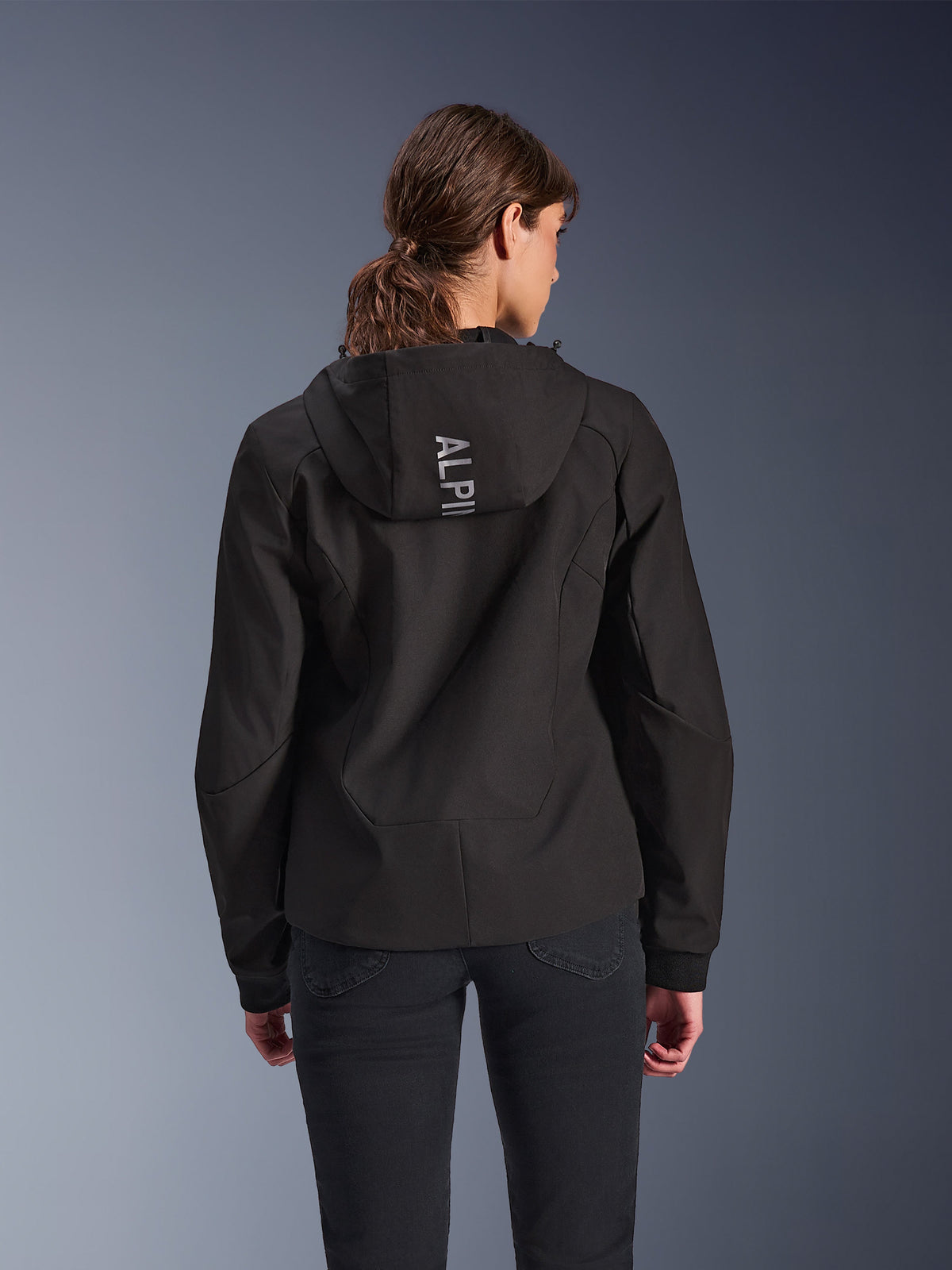 Alpinestars Stella Radium Tech Hoodie, stedelijke motorhoodie voor dames in zwart, achteraanzicht met capuchon met verticale zilveren Alpinestars-branding, lichtgewicht 3-laags winddichte shell, moderne sportieve pasvorm