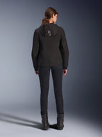 Alpinestars Stella Radium Tech Hoodie voor dames, zwart, achteraanzicht van model met lichtgewicht 3-laags winddichte tech hoodie met Alpinestars-logo op de capuchon, gecombineerd met zwarte broek en laarzen, stedelijke motorkleding