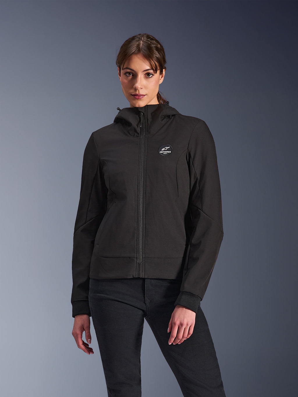 Alpinestars Stella Radium Tech Hoodie, dames motorjas met capuchon, zwart, ontwerp met ritssluiting, rond logo op de borst en capuchon, technische urban motorkleding, gedragen door model