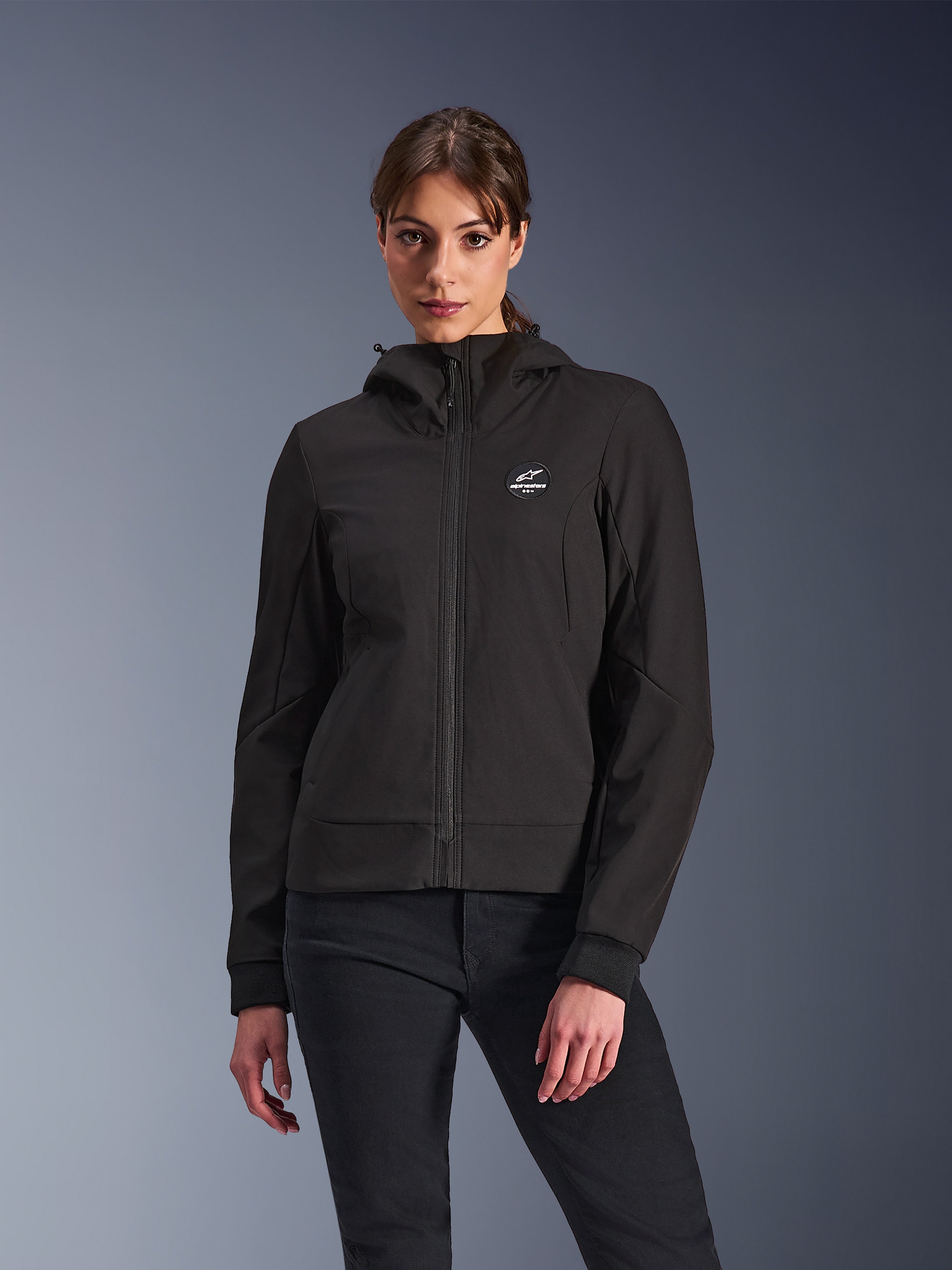 Alpinestars Stella Radium Tech Hoodie, dames motorjas met capuchon, zwart, ontwerp met ritssluiting, rond logo op de borst en capuchon, technische urban motorkleding, gedragen door model