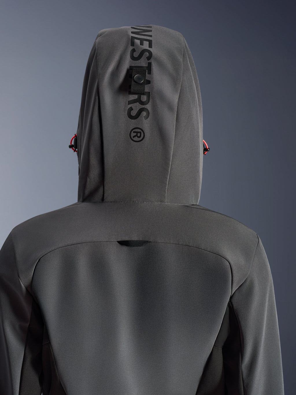 Alpinestars Stella Radium Tech Hoodie pour femme, Deep Gray Black, vue rapprochée de dos montrant la capuche avec marquage vertical et boucle d'attache, détails de cordons rouges, construction technique à 3 couches coupe-vent pour la moto urbaine.
