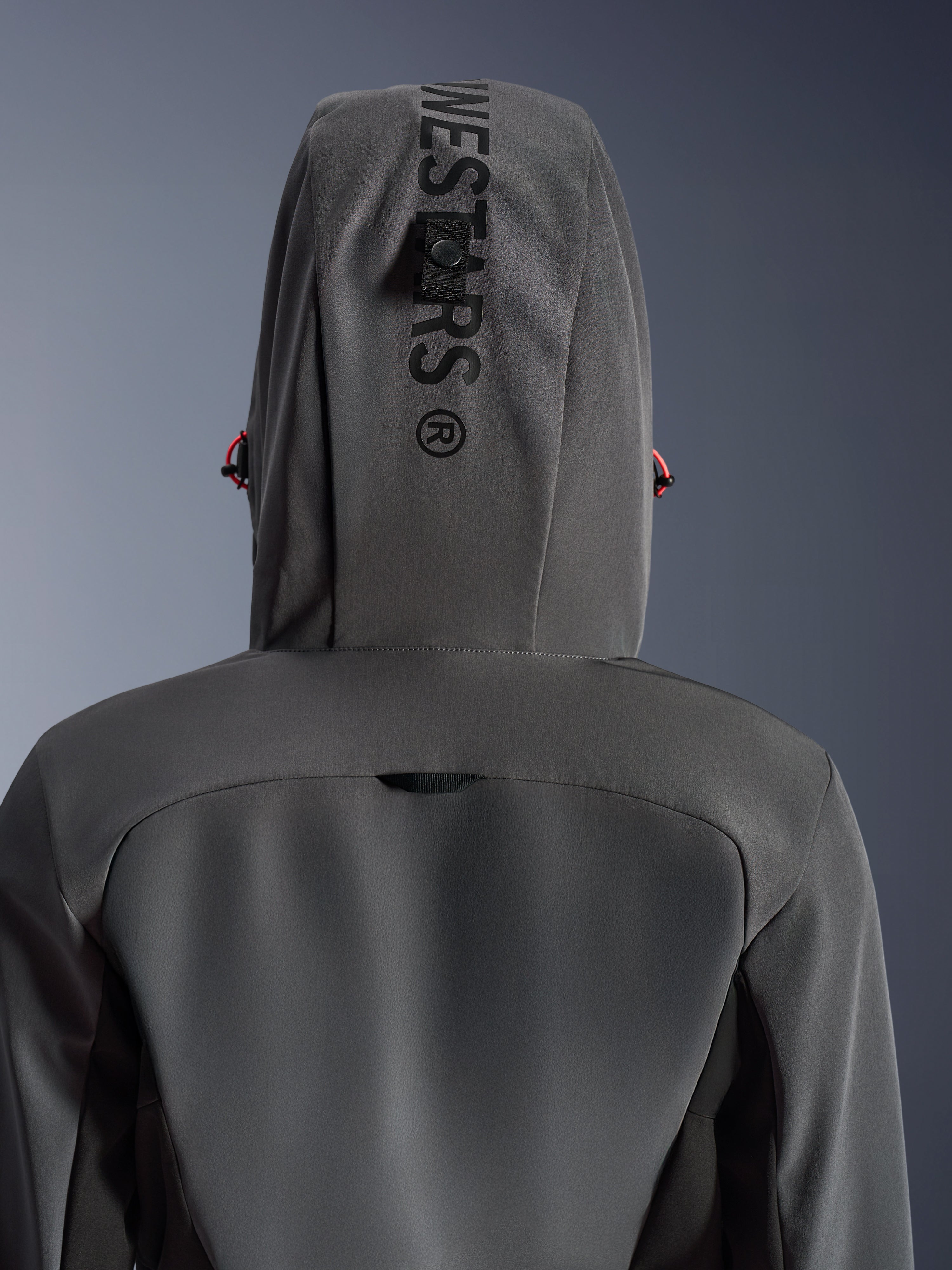 Alpinestars Stella Radium Tech Hoodie pour femme, Deep Gray Black, vue rapprochée de dos montrant la capuche avec marquage vertical et boucle d'attache, détails de cordons rouges, construction technique à 3 couches coupe-vent pour la moto urbaine.