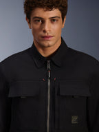 Alpinestars Bryon Water Resistant Overshirt, noire, vue rapprochée de la fermeture éclair frontale et des poches de poitrine, texture en toile cirée durable, design urbain minimaliste avec finitions de la marque et étiquette logo tissée