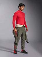 Alpinestars ZX Evo V3 Langarm-Top in Rot, feuerfeste Basisschicht für den Automobilsport, getragen mit einer olivgrünen Rennsport-Hose und schwarz-roten Rennschuhen, professionelle Motorsportausrüstung, Studio-Porträt