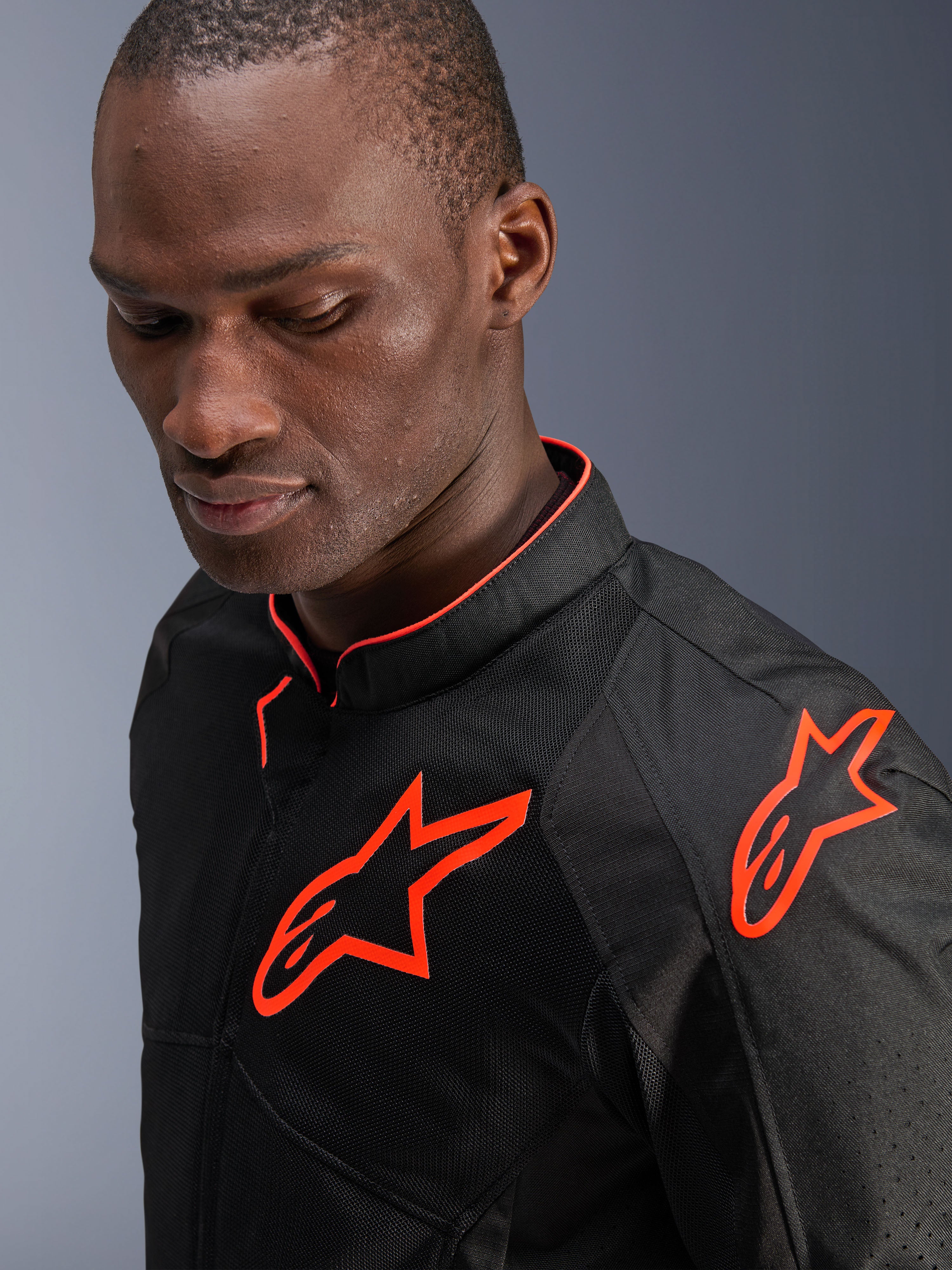 Veste Alpinestars Viper Air V4, noir et rouge fluo, portée par un mannequin homme, vue rapprochée montrant des panneaux en textile mesh et des logos Alpinestars rouge fluo éclatant sur la poitrine et l'épaule, équipement de route sportif pour moto