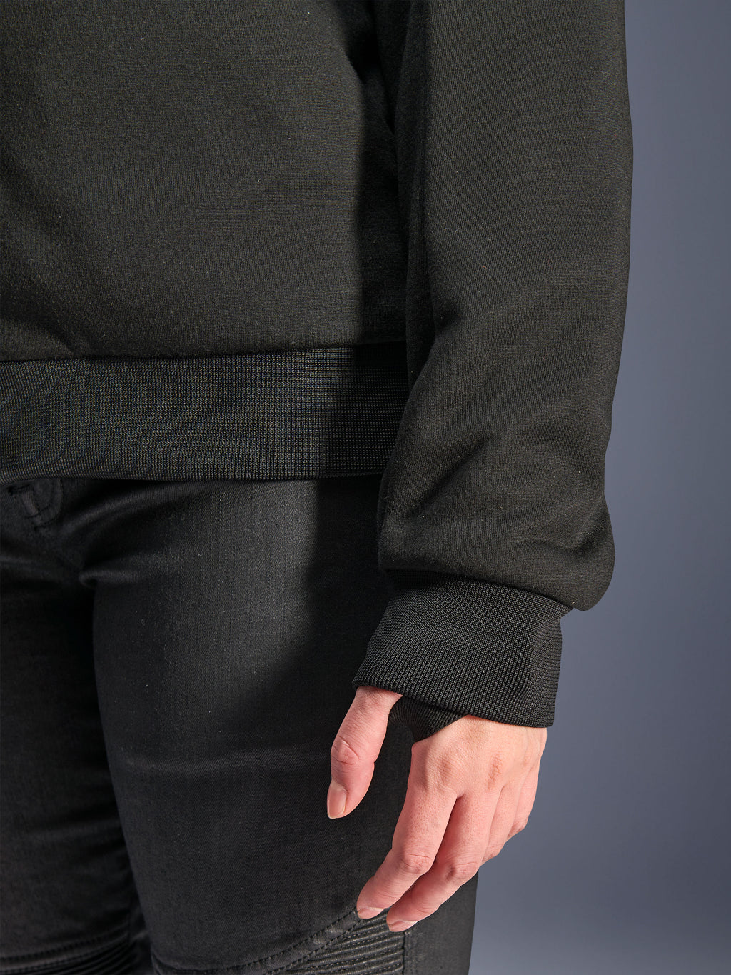 Alpinestars Stella Chrome V2 Sport Hoodie, noir, gros plan sur le poignet en bord-côte avec passage pour le pouce et l'ourlet de la taille en bord-côte, matériau polaire technique pour la conduite moto urbaine