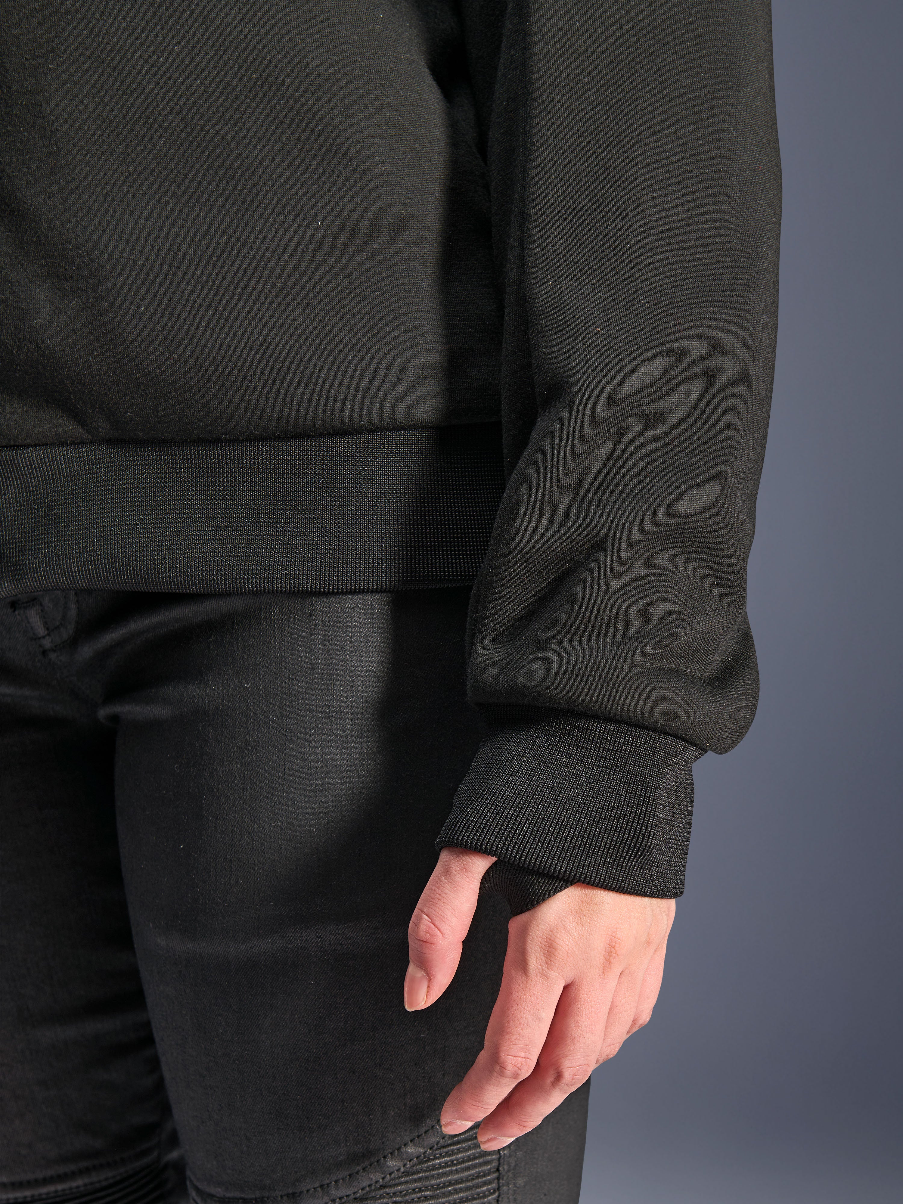 Alpinestars Stella Chrome V2 Sport Hoodie, noir, gros plan sur le poignet en bord-côte avec passage pour le pouce et l'ourlet de la taille en bord-côte, matériau polaire technique pour la conduite moto urbaine