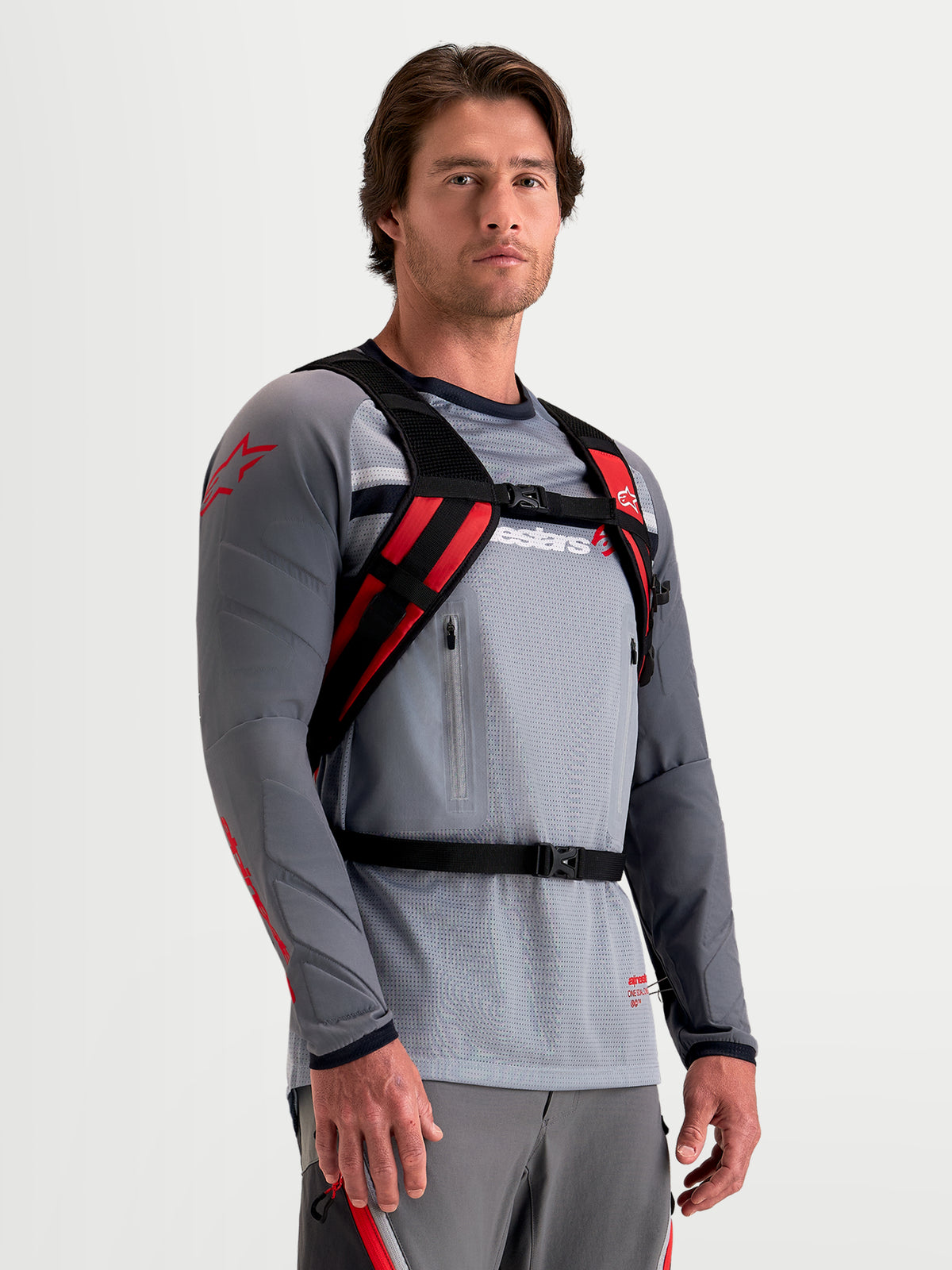 Alpinestars AT-9 Rucksack, Motocross-Rucksack in Schwarz und Leuchtrot, getragen von einem Model zur Präsentation des gepolsterten Gurtsystems und des sicheren Verschlusssystems