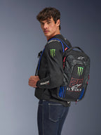 Alpinestars FQ20 City Hunter V2 Monster rugzak, motorrugzak, zwart met fluo rood, blauw en groen, voorzien van Monster Energy en Fabio Quartararo 'El Diablo' branding, gedragen door een model met een zwart motorjack en jeans, gestroomlijnd ontwerp voor stedelijke rijders