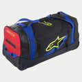 Alpinestars Komodo Reisetasche, Rollentasche für Ausrüstung, Schwarz, Blau, Rot und Fluo-Gelb, mit blauen Gurtbandgriffen, einem roten Seitenpaneel und fluoreszierend gelben Logos, robuste Konstruktion mit Rollen für den Transport von Motocross- und Rennausrüstung