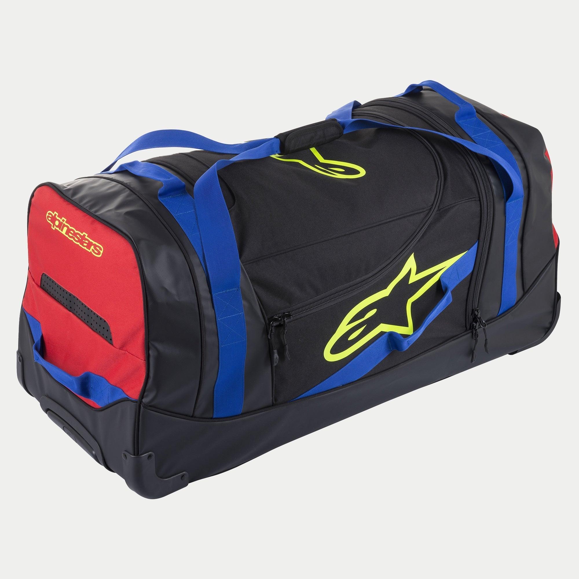 Sac de voyage Alpinestars Komodo, sac d'équipement à roulettes, noir, bleu, rouge et jaune fluo, doté de poignées en sangle bleues, d'un panneau latéral rouge et de logos jaune fluo, construction robuste à roulettes pour le transport d'équipement de motocross et de course