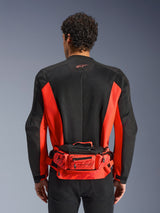 Alpinestars MM93 heuptas, rood en zwart, gedragen over een zwart en rood motorjack, voorzien van Marc Marquez 93-branding, verstelbare riem en vakken met ritssluiting, functioneel op de racerij geïnspireerd accessoire