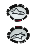 Alpinestars GP Tech, sliders de genou pour moto, blanc et noir, ensemble de sliders gauche et droit avec coques en plastique blanc et logos Astar noirs, support auto-agrippant avec texte « ONE GOAL ONE VISION », équipement de course haute performance