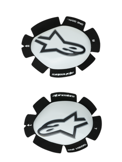 Sliders de genou Alpinestars GP Plus, blanc et noir, protections de genou pour la course moto, paire présentant les sliders gauche et droit avec surfaces en plastique blanc et logos Astars noirs, support Velcro noir festonné avec marquages « ONE GOAL » et « ONE VISION »