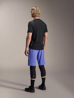 Mannequin homme de dos portant le short Alpinestars A-Aria Lite en bleu Baja, associé à un maillot noir à manches courtes et des protections de genoux noires, tenue de cyclisme VTT professionnelle pour le trail.