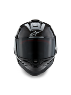 Casque Alpinestars Supertech R10 Solid, vue de face, finition carbone noir mat et brillant, trame de fibre de carbone apparente, logo Alpinestars blanc, écran fumé foncé, casque de moto de course aérodynamique