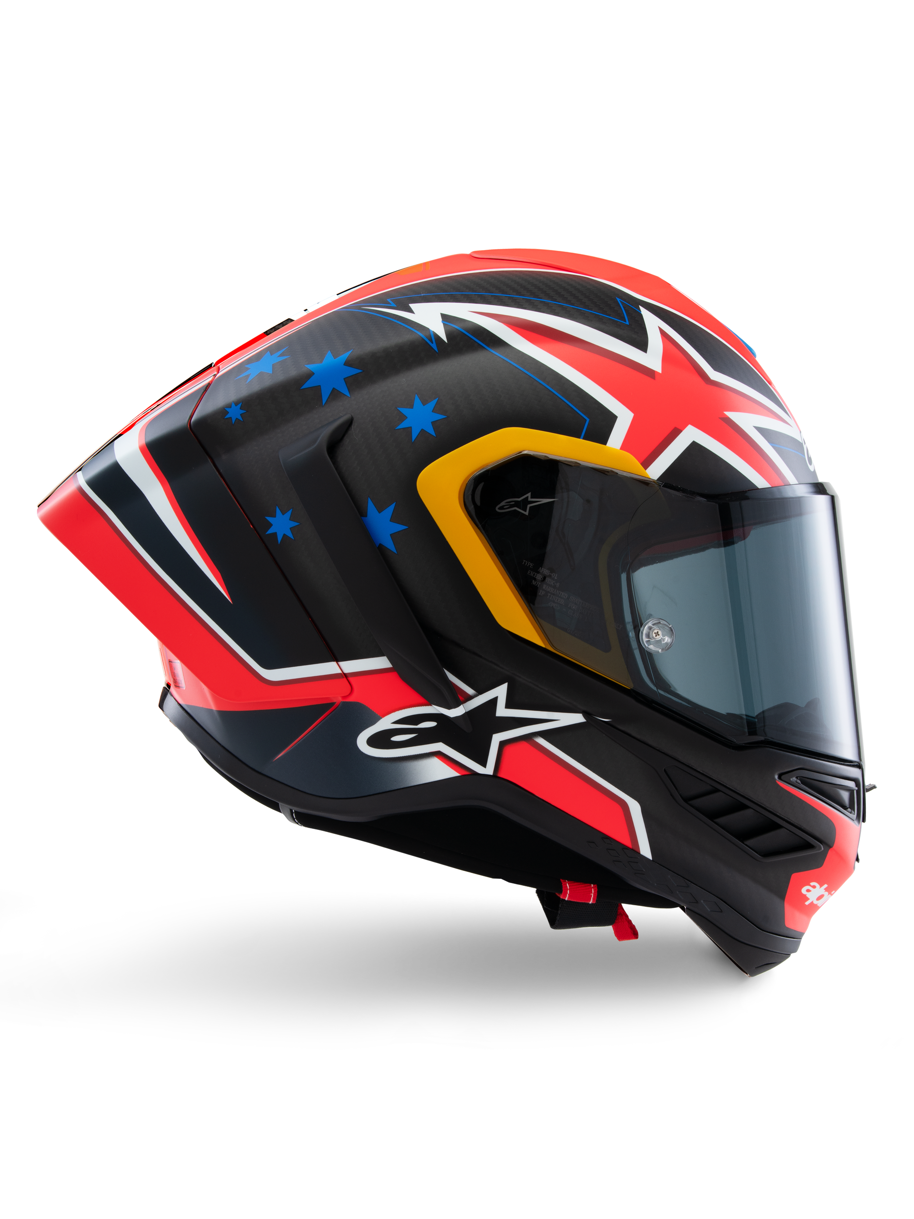 Casque Alpinestars Supertech R10 Miller Limited Edition, casque intégral de course, carbone mat avec graphismes rouges, blancs et bleus, motifs d'étoiles bleues et liseré de visière jaune, profil aérodynamique avec écran fumé foncé, équipement de sécurité moto haute performance