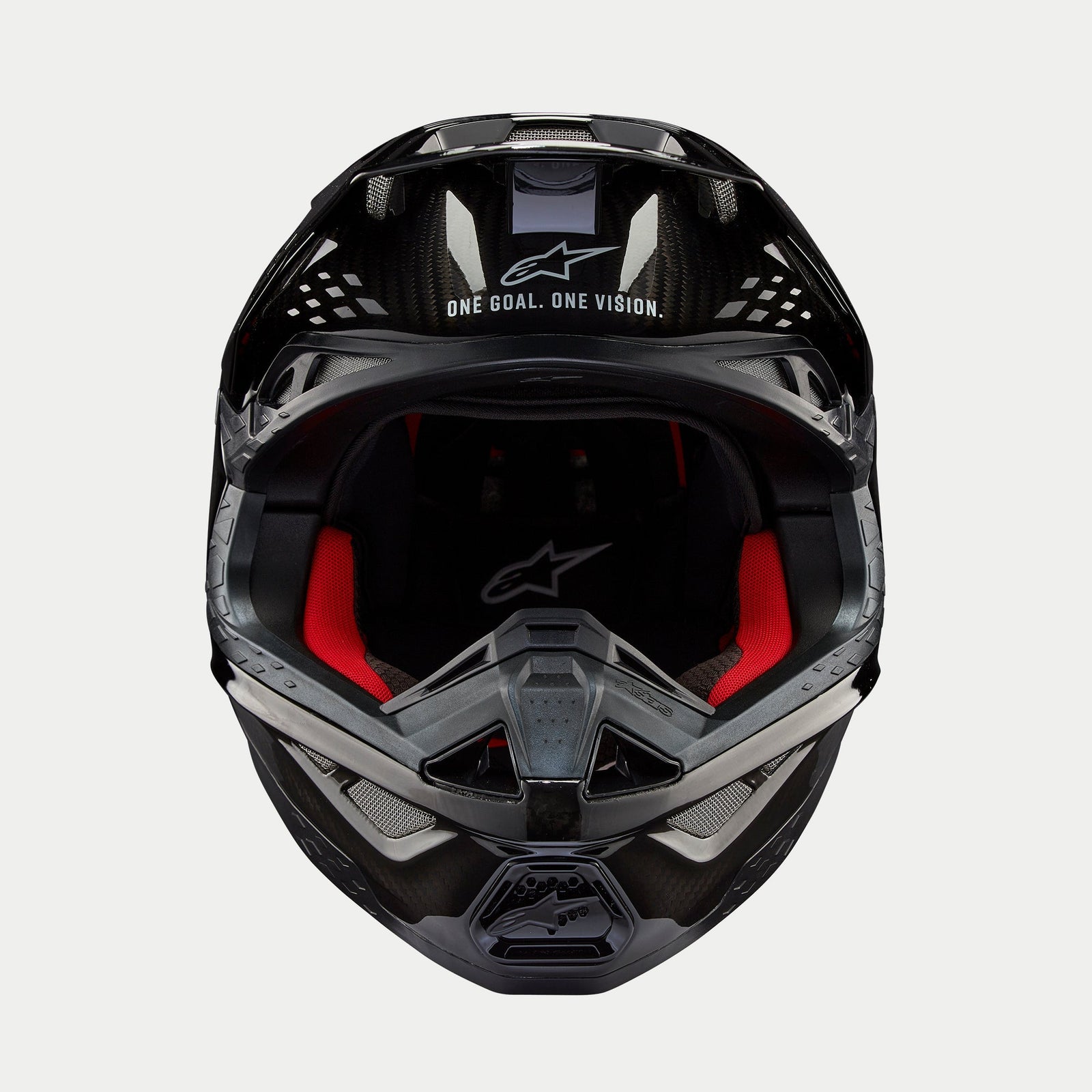 Casque Alpinestars Supertech M10 Solid, casque de motocross, carbone noir brillant, vue de face montrant la doublure intérieure rouge, la coque en fibre de carbone et le slogan « ONE GOAL. ONE VISION. » sur la visière