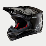 Casque Alpinestars Supertech M10 Solid, casque de motocross, carbone noir brillant avec tissage de fibres apparent, doté du logo Alpinestars blanc et du marquage SM10, doublure intérieure rouge, design aérodynamique avec de multiples orifices de ventilation