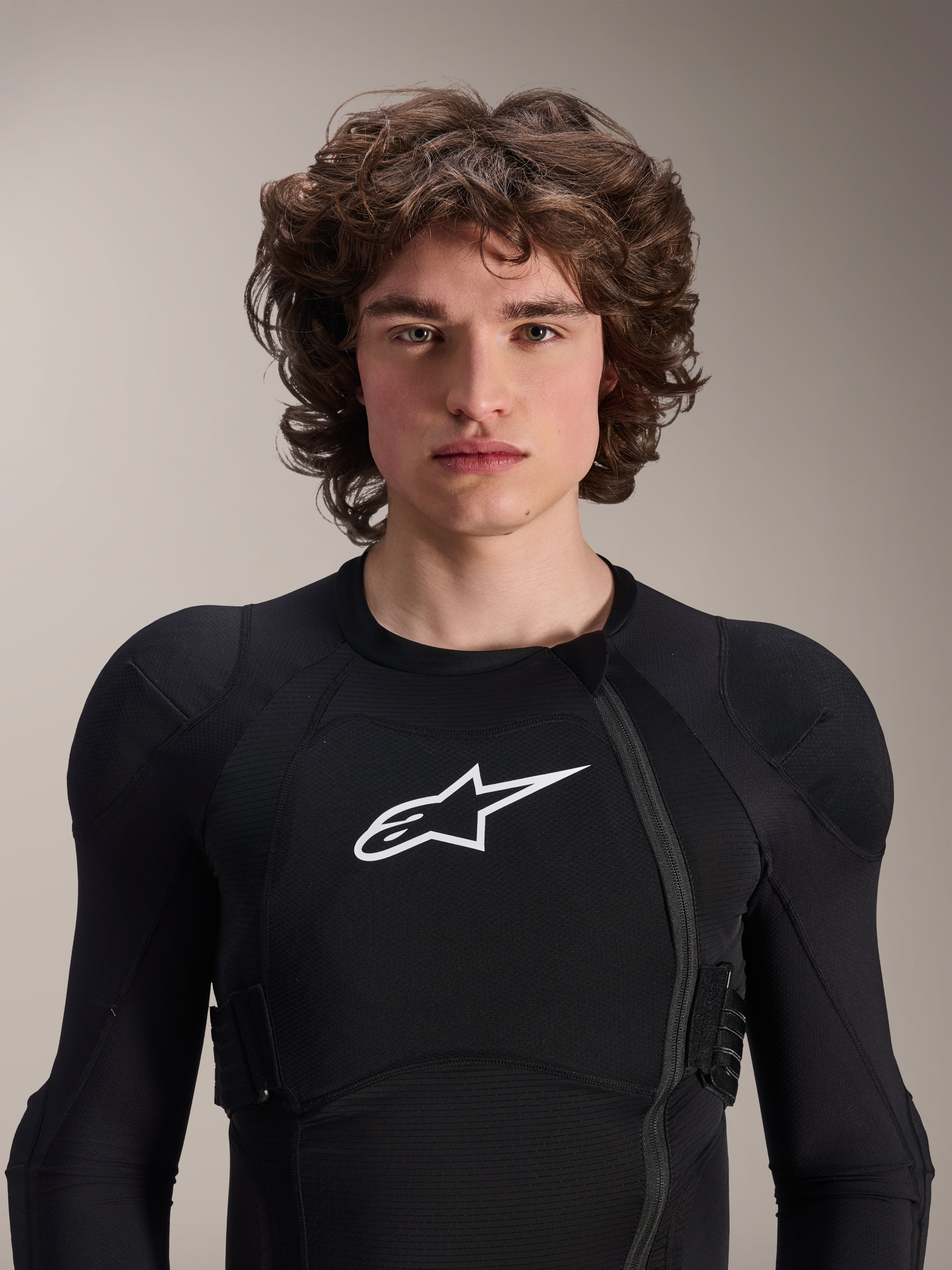 Modèle masculin portant une veste de protection Alpinestars A-Impact Plasma à manches longues, noire avec logo Astars blanc, dotée d'une fermeture éclair frontale décalée et d'un rembourrage intégré, équipement de protection VTT professionnel