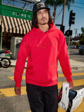 Alpinestars Emergent Oversized Hoodie, rood, 3D-geborduurd Astars-logo op de borst, gedragen met een zwarte broek en een baseballpet terwijl de persoon een witte motorcrosshelm vasthoudt, casual urban streetwear-stijl