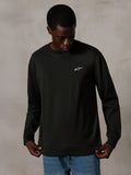 Alpinestars Essentials Ageless LS Tee, Langarmshirt, Off Black, mit einem kleinen weißen Logo auf der Brust, getragen von einem Modell mit blauen Jeans, lässige Lifestyle-Streetwear