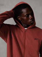 Alpinestars Essentials Ageless Zip Hoodie, Brick red, casual lifestyle streetwear, hood up with hand behind head, small black Astars logo on chest, relaxed fit fleece hoodie