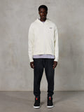 Alpinestars Essentials Ageless Zip Hoodie, lässige Streetwear, Off-White mit dezentem schwarzem Logo auf der Brust, durchgehender Reißverschluss vorne, Kapuzendesign, entspannte Passform, kombiniert mit schwarzer Jogginghose und Sneakern