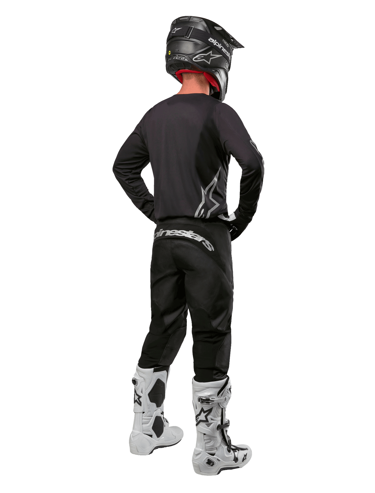 Alpinestars 2024 Fluid Graphite Gear Set, Motocross rider viewed from the back, graphite gray jersey and pants with silver Alpinestars branding, black helmet and white motocross boots, athletic fit gear for off-road riding