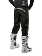 Alpinestars 2024 Fluid Graphite Gear Set, back view of black and gray motocross pants with white Alpinestars branding on the seat, worn with white and black motocross boots, specialized off-road racing gear