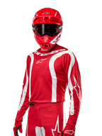 Alpinestars 2024 Fluid Lurv Trikot, Motocross-Renntrikot, Mars-Rot und Weiß, getragen mit passendem rotem Helm und Handschuhen, markantes sportliches Design mit weißen geschwungenen Streifen und Alpinestars-Branding