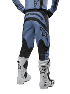 Alpinestars 2024 Fluid Lurv Pants, pantalon de motocross, bleu clair et noir, vue arrière montrant les panneaux renforcés noirs et le grand logo de la marque, associé à des bottes de motocross blanches et noires, équipement de course professionnel pour le tout-terrain
