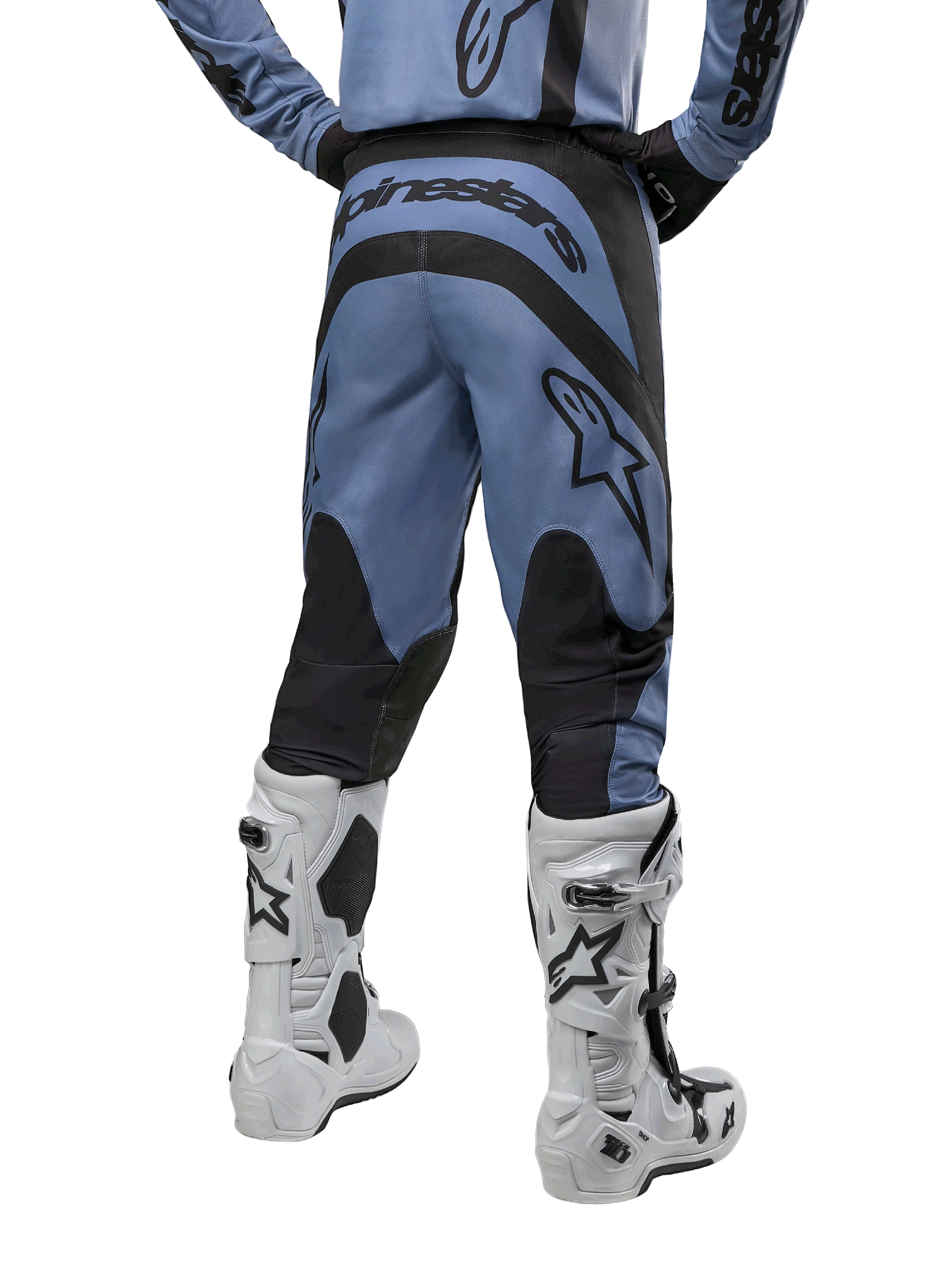 Alpinestars 2024 Fluid Lurv Pants, pantalon de motocross, bleu clair et noir, vue arrière montrant les panneaux renforcés noirs et le grand logo de la marque, associé à des bottes de motocross blanches et noires, équipement de course professionnel pour le tout-terrain