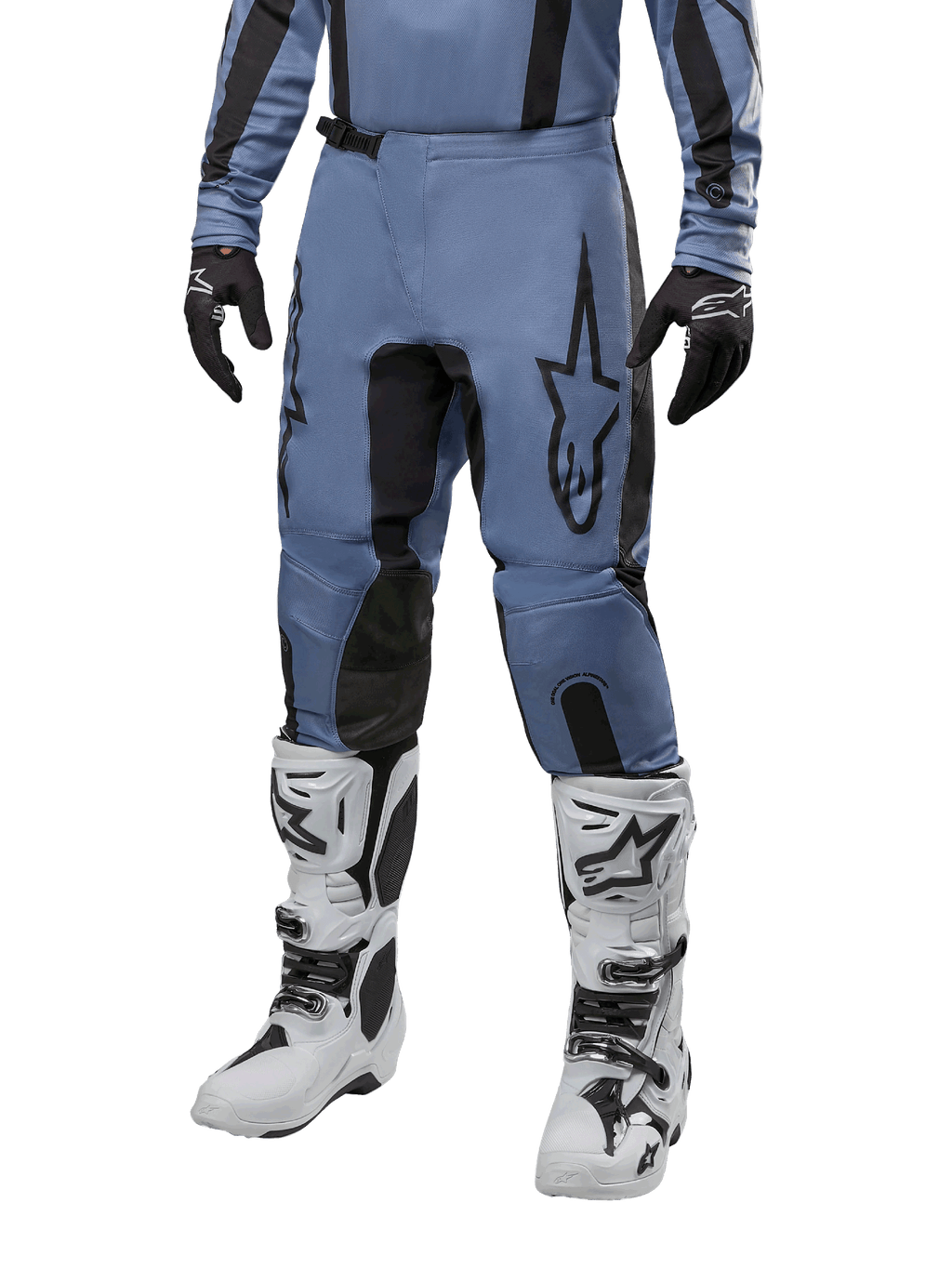 Pantalon Alpinestars Fluid Lurv 2024, pantalon de motocross, bleu clair et noir, porté avec un maillot à manches longues assorti et des bottes de motocross blanches, doté d'un logo étoile noire sur la cuisse et de panneaux intérieurs de genoux renforcés, vue de face sur fond blanc