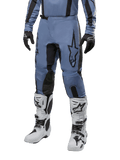 Pantalon Alpinestars Fluid Lurv 2024, pantalon de motocross, bleu clair et noir, porté avec un maillot à manches longues assorti et des bottes de motocross blanches, doté d'un logo étoile noire sur la cuisse et de panneaux intérieurs de genoux renforcés, vue de face sur fond blanc