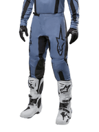 Pantalon Alpinestars Fluid Lurv 2024, pantalon de motocross, bleu clair et noir, porté avec un maillot à manches longues assorti et des bottes de motocross blanches, doté d'un logo étoile noire sur la cuisse et de panneaux intérieurs de genoux renforcés, vue de face sur fond blanc