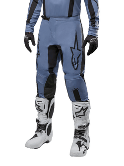 Alpinestars 2024 Fluid Lurv Hose, Motocross-Hose, Hellblau und Schwarz, getragen mit passendem Langarm-Trikot und weißen Motocross-Stiefeln, mit markantem schwarzen Stern-Logo auf dem Oberschenkel und verstärkten Knie-Innenpaneelen, Vorderansicht auf weißem Hintergrund