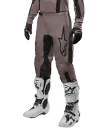 Alpinestars 2024 Fluid Lurv Hose, Motocross-Hose, Mud Black und Schwarz, mit Alpinestars-Logo, getragen mit schwarzen Handschuhen und weißen Motocross-Stiefeln, sportliches Design für Offroad-Rennsport