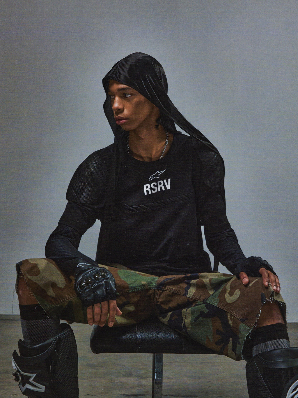 T-shirt Alpinestars RSRV Nucleon SS, noir avec logo RSRV blanc, porté avec pantalon camouflage et équipement de protection tactique