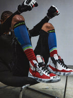 Alpinestars RSRV Legacy Shoe, chaussures streetwear premium, rouges, blanches et noires, portées avec chaussettes colorées à rayures bleues, vertes et rouges, style urbain lifestyle