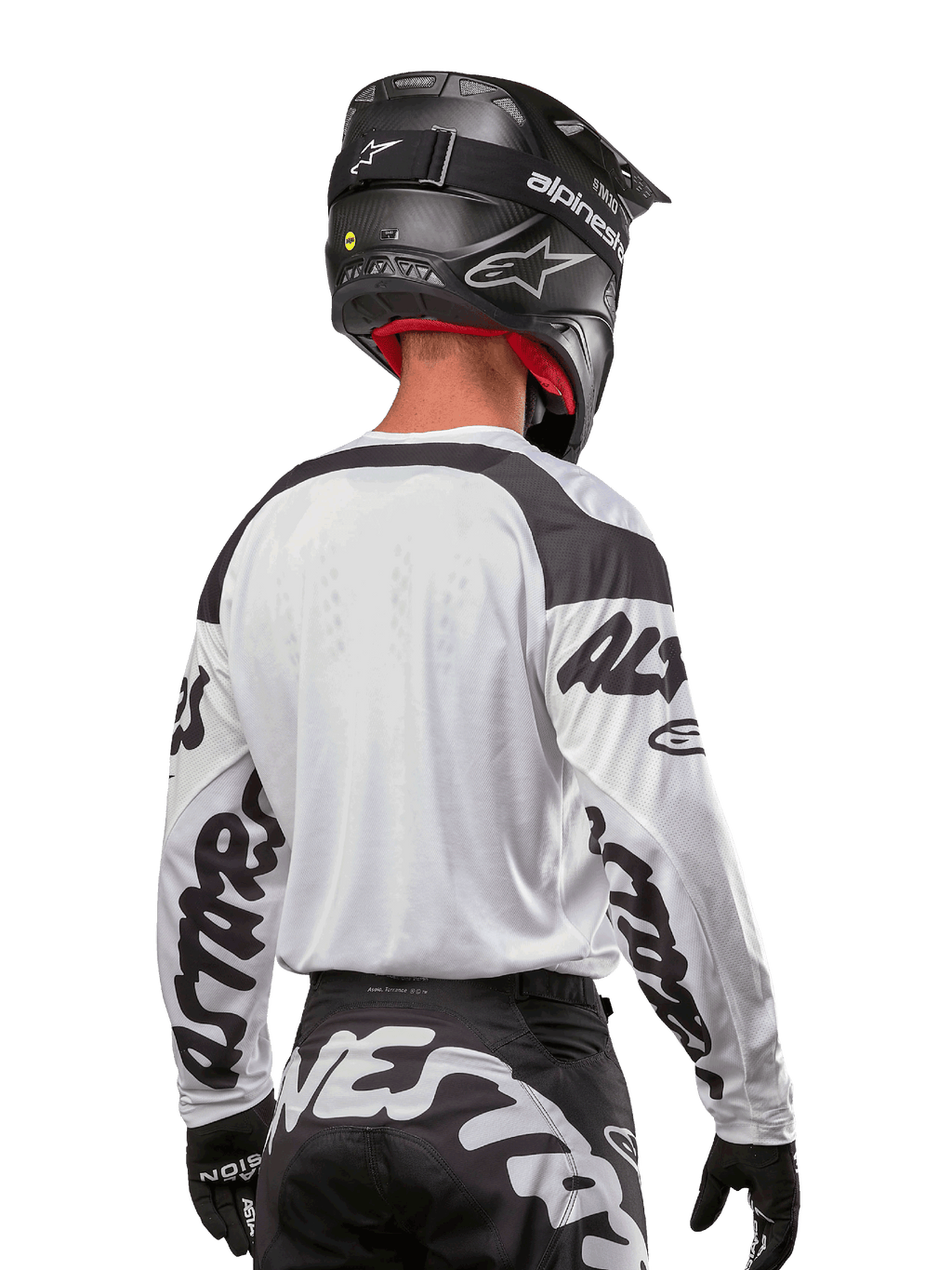 Alpinestars 2024 Racer Hana Trikot, Weiß und Schwarz, Rückansicht zeigt ergonomische Passform und markantes Ärmel-Branding, kombiniert mit einem schwarzen Motocross-Helm und dazu passender schwarz-weißer Hose, Hochleistungs-Rennausrüstung für Offroad-Fahrten