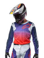 Alpinestars 2024 Racer Hoen Trikot, Motocross-Trikot, Farbverlauf von Lila zu leuchtendem Orange mit dunkelblauen Ärmeln, hellgraue Schultereinsätze, getragen mit passender Rennhose und Helm, komplette Offroad-Fahrausrüstung