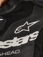 Close-up van het Alpinestars Stella GP-R7 2-delig lederen motorpak in het zwart, met geperforeerde lederen panelen, een groot wit Alpinestars-logo op de borst en ademende stretchstof gedeeltes.