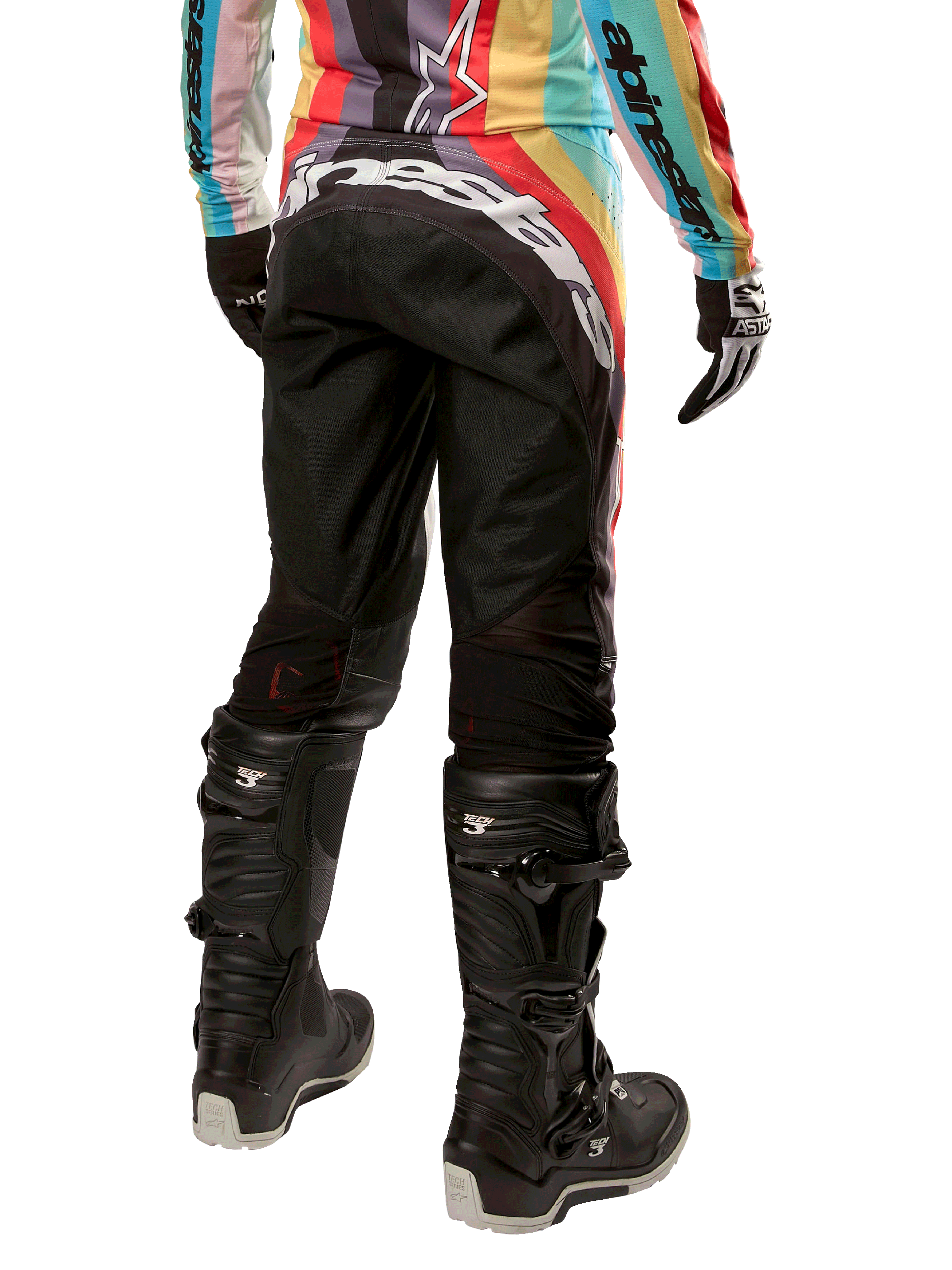 Pantalon femme Alpinestars Stella Techstar 2024, pantalon de motocross, noir multicolore, vue arrière présentant un marquage blanc imposant sur le fessier, porté avec des bottes Tech 3 noires et un maillot multicolore assorti, équipement de course tout-terrain professionnel